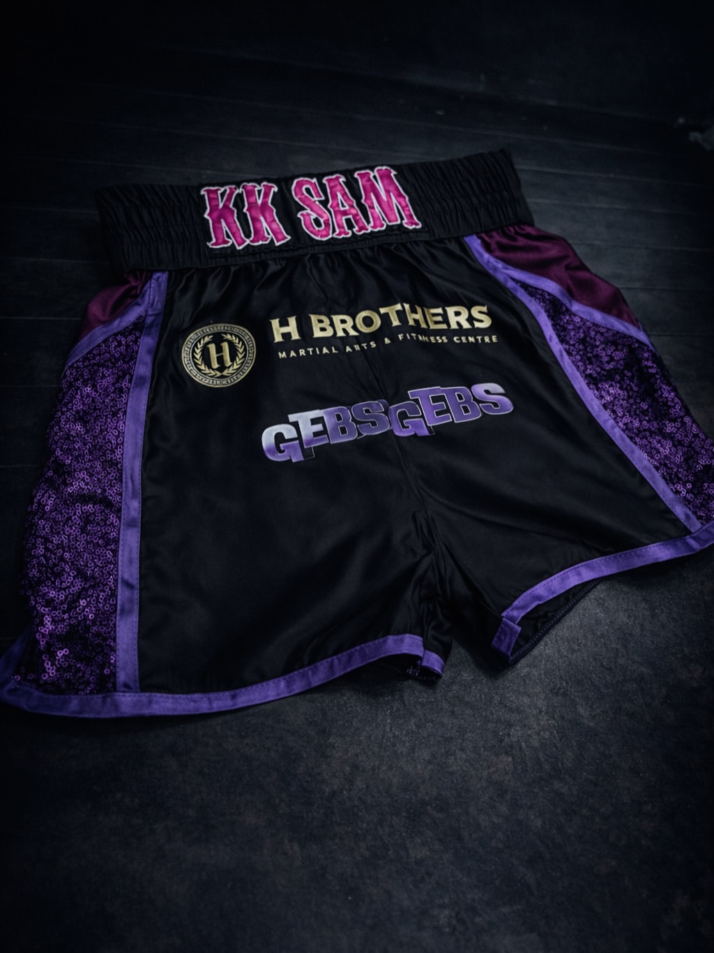 Black and purple custom KK Sam Muay Thai shorts, front view