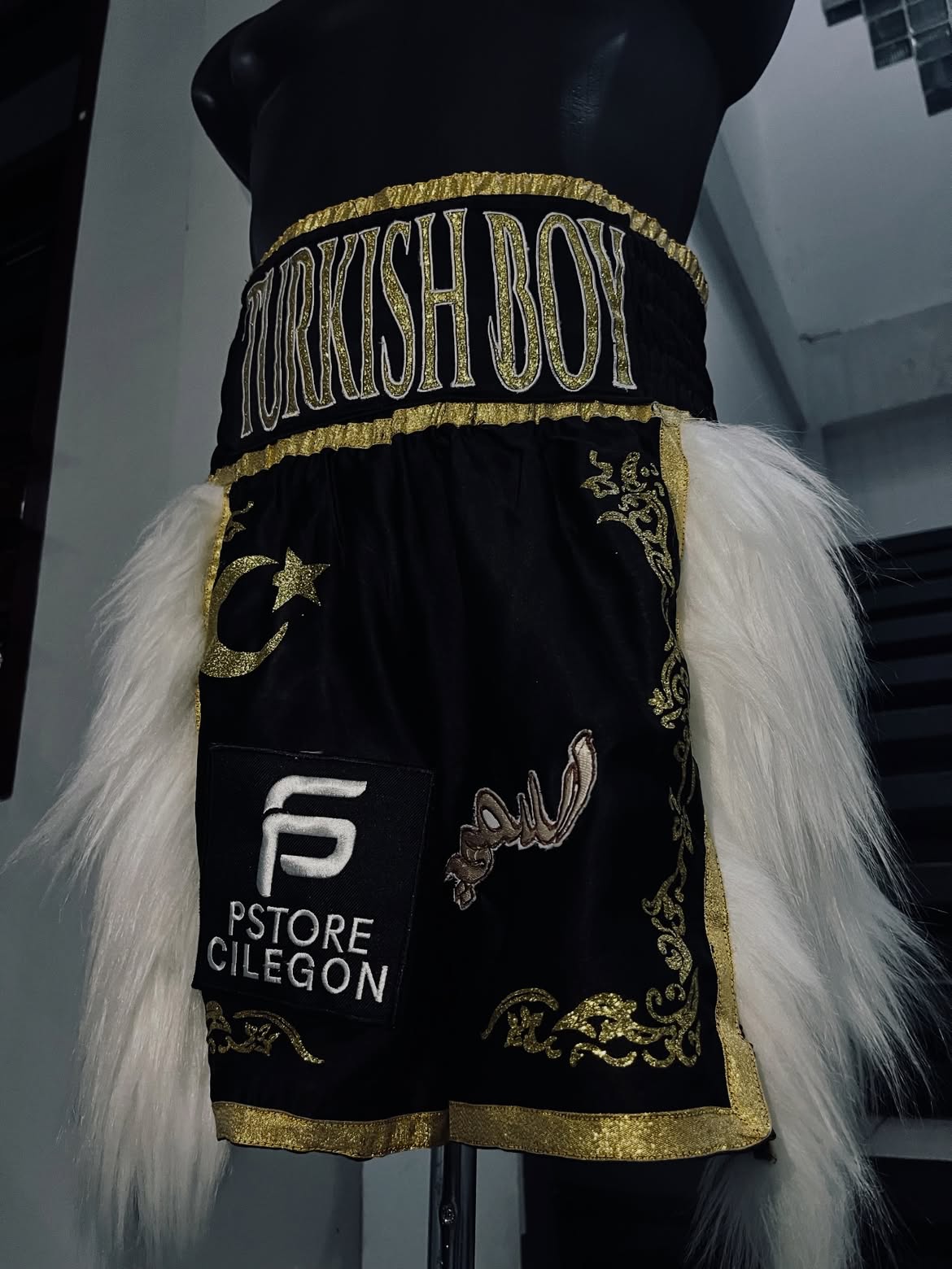 Black and gold Turkish Boy boxing trunks with white side trim.
