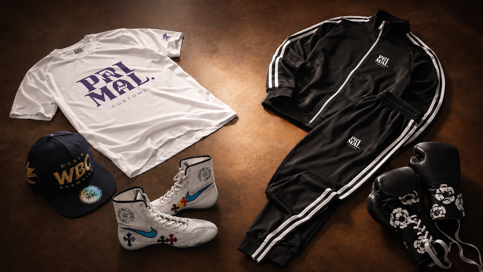 Flat lay of Primal team apparel and custom fight gear — t-shirt, tracksuit, shoes, gloves and cap.