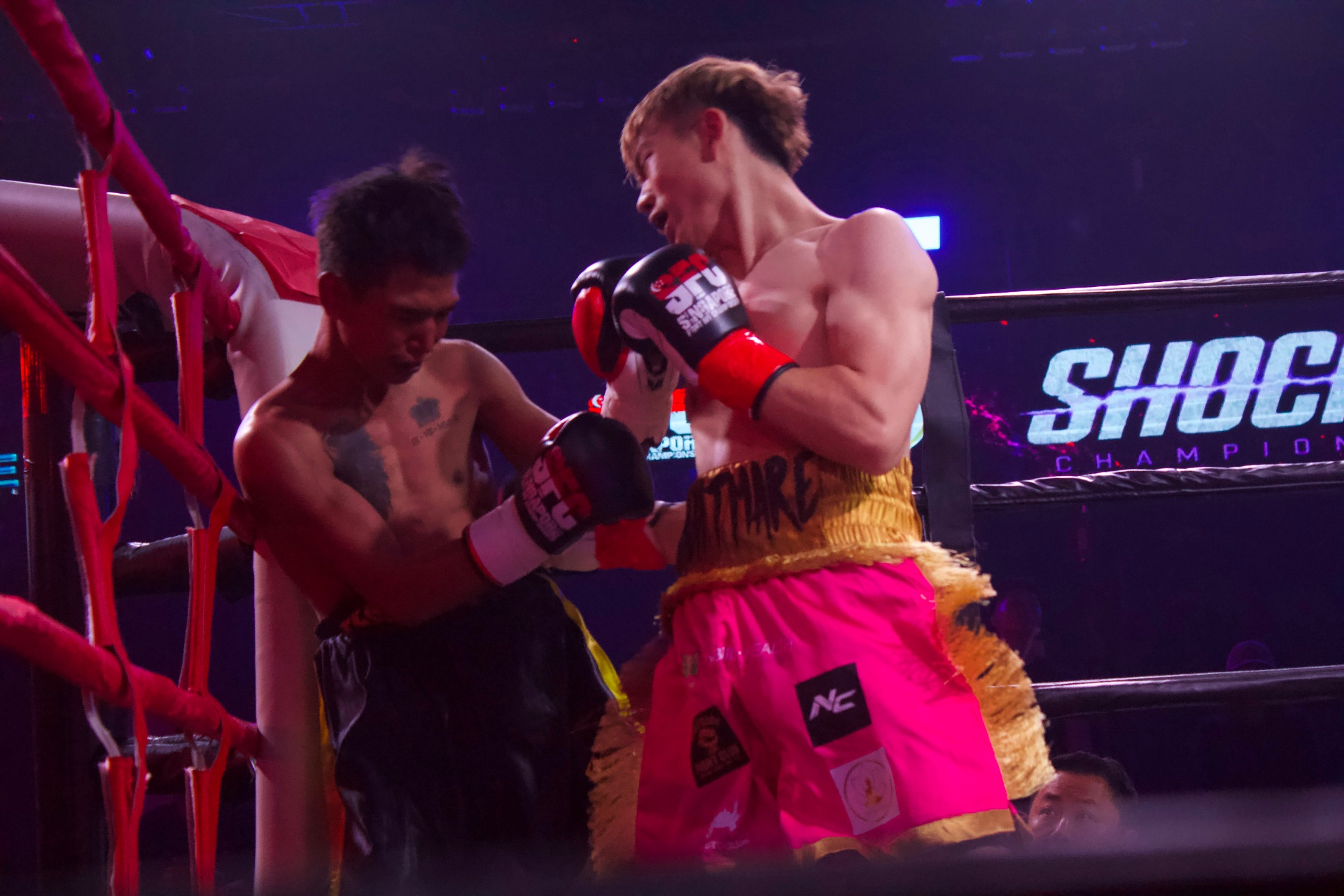 Nick Chua 'Nightmare' throwing a punch in fuchsia and gold fringe Muay Thai shorts.