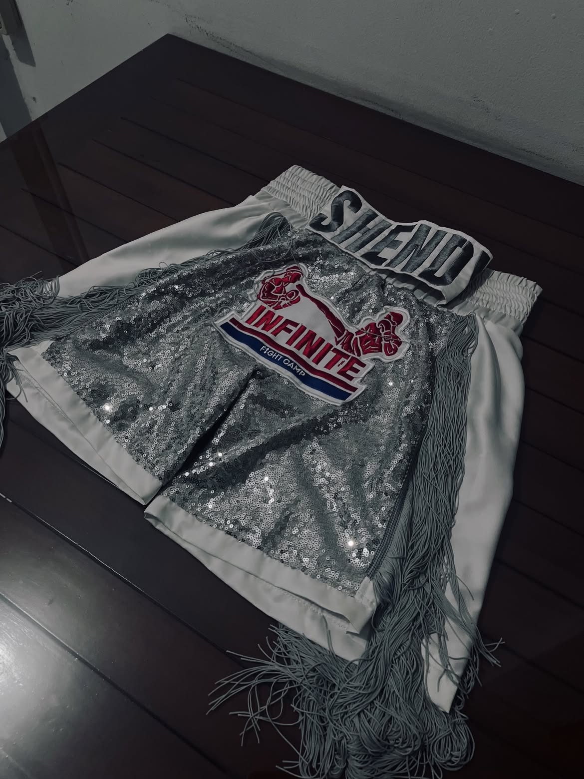 White and silver INFINITE boxing trunks with sequin panels and fringe.